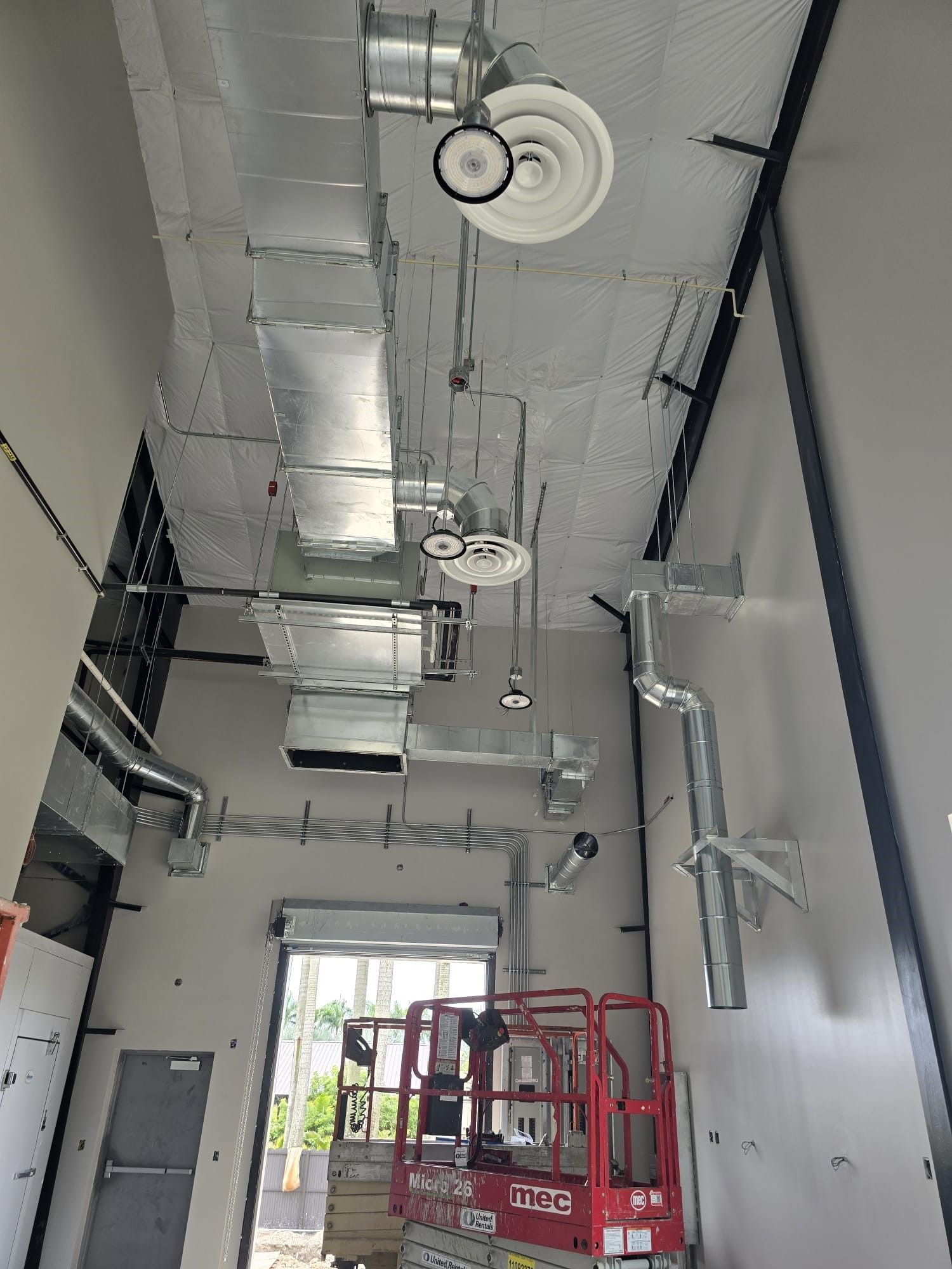 Industrial interior with exposed ductwork and a red lift truck near a doorway