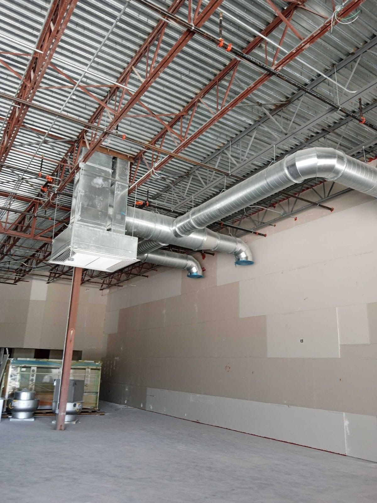 Empty industrial warehouse with exposed ductwork and unfinished walls under construction