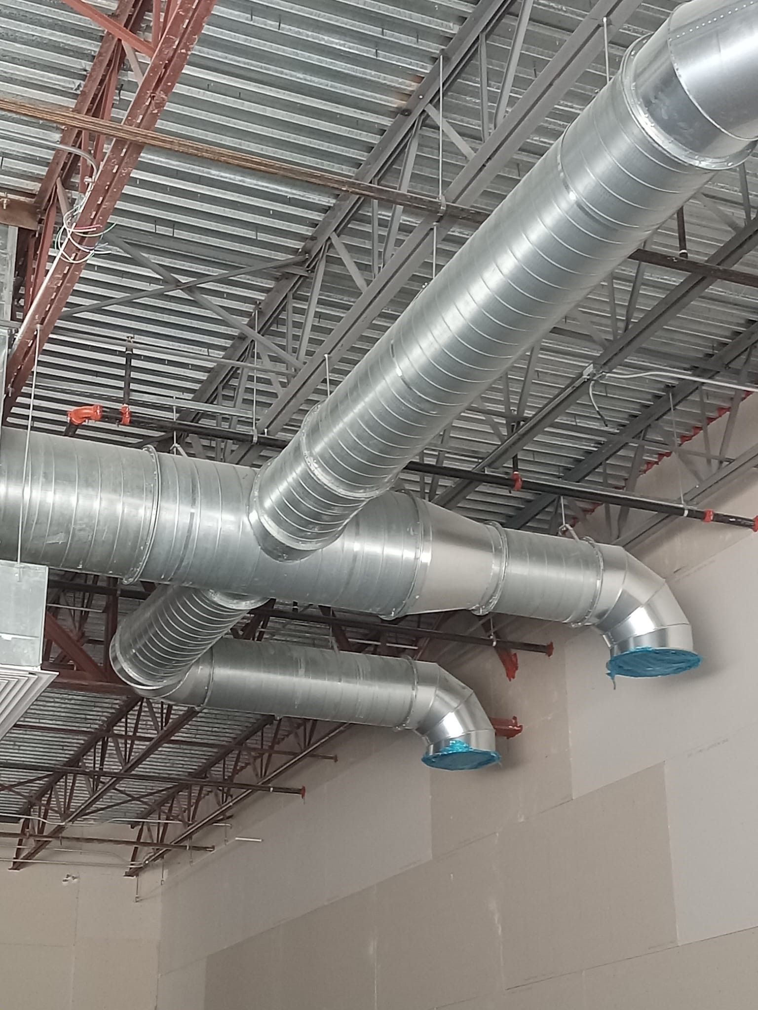 Exposed silver HVAC ductwork and metal ceiling framing in a building under construction