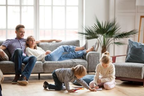 Family relaxing in a bright living room while two children play on the floor
