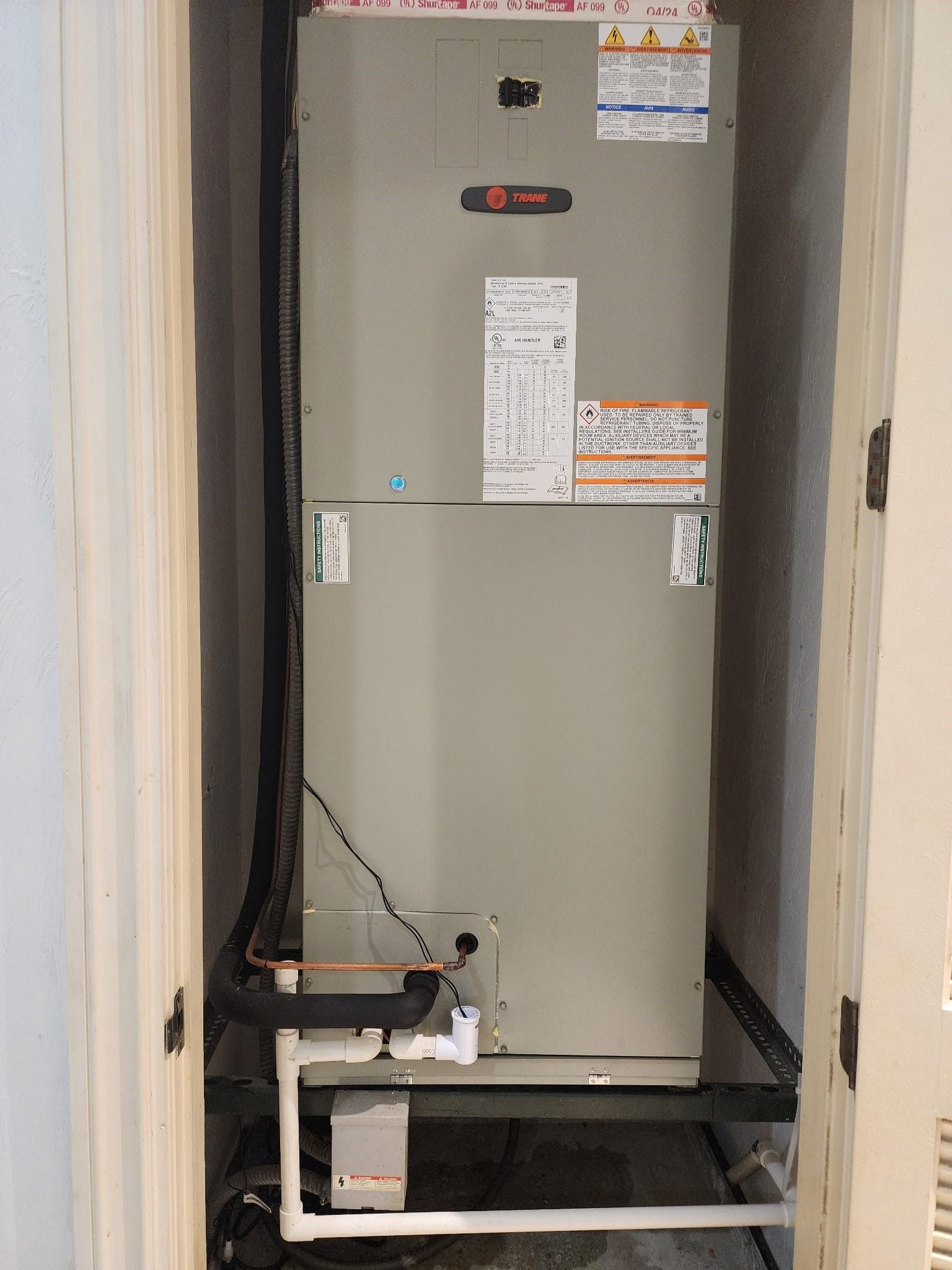 Open utility closet with a large gray HVAC/furnace unit and visible piping inside.