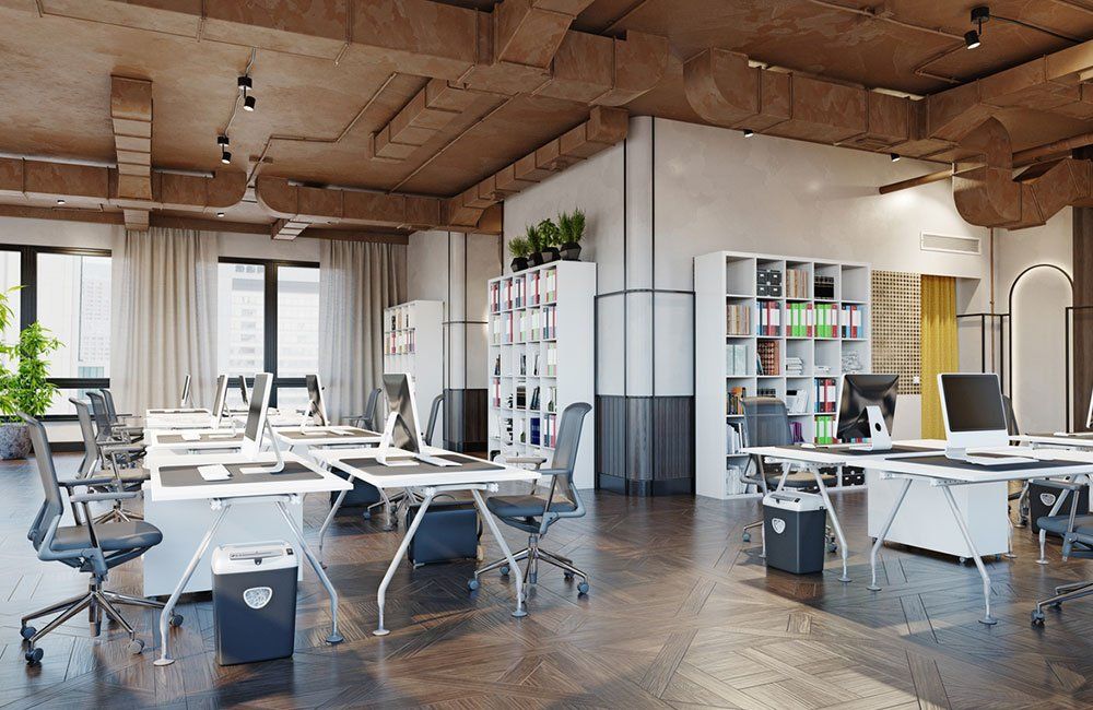 Modern coworking office with white desks, chairs, bookshelves, and indoor plants under a wooden ceiling.