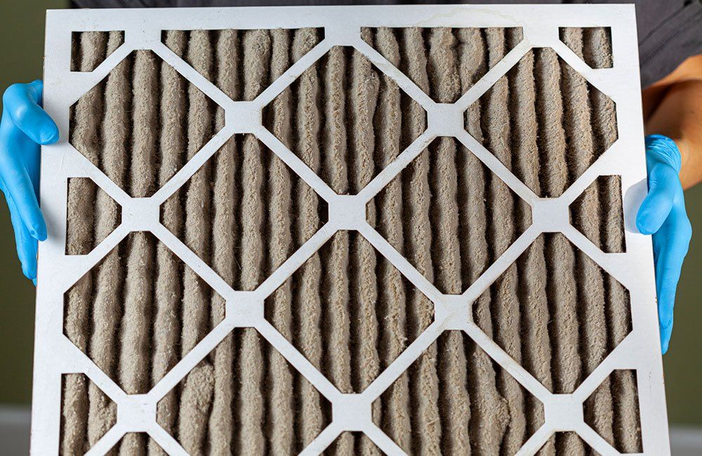 White air filter with blue tabs, held over a corrugated filter media background