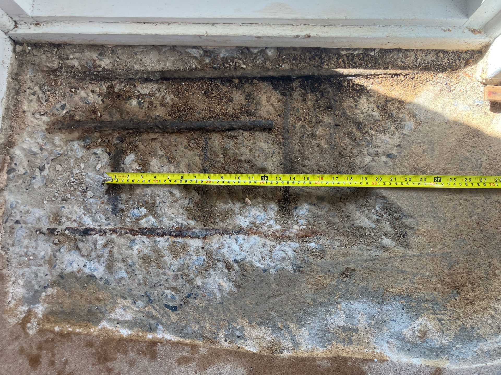 Mold and water damage on a wall or ceiling corner, with a yellow measuring tape across the stain.