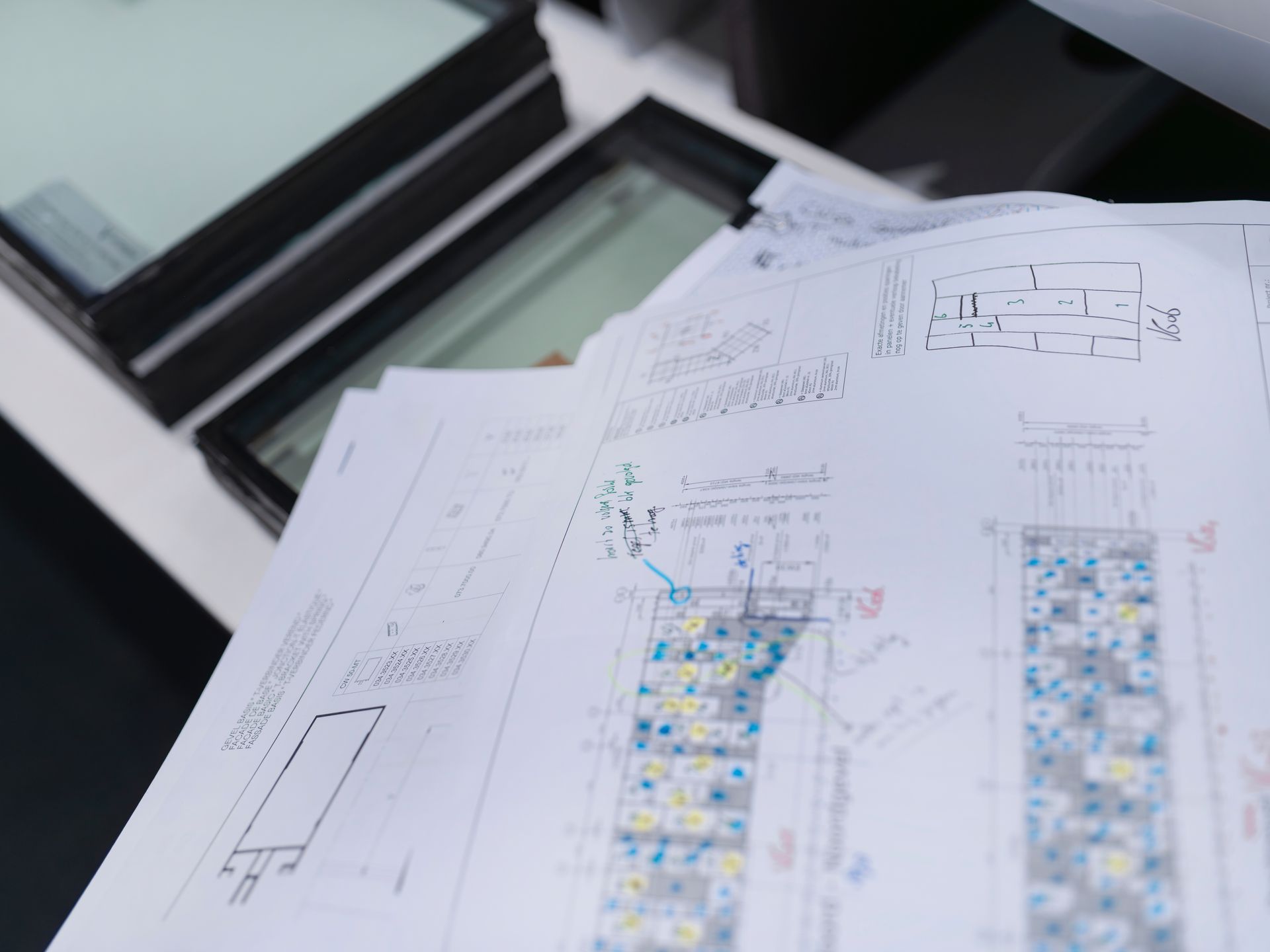 Architectural plans spread on a drafting table beside a window.