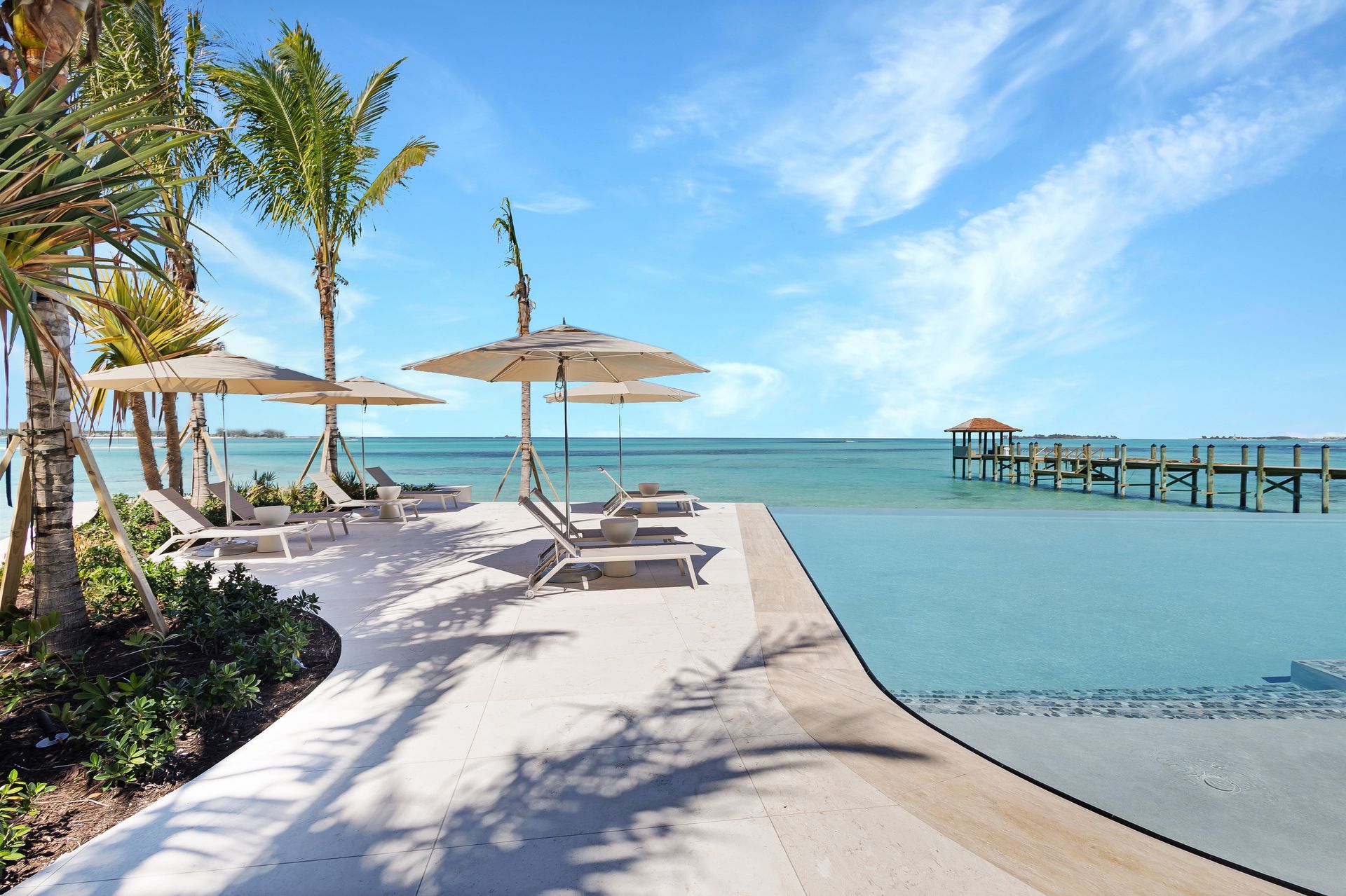 A swimming pool with chairs and umbrellas next to the ocean in Nassau Bahamas