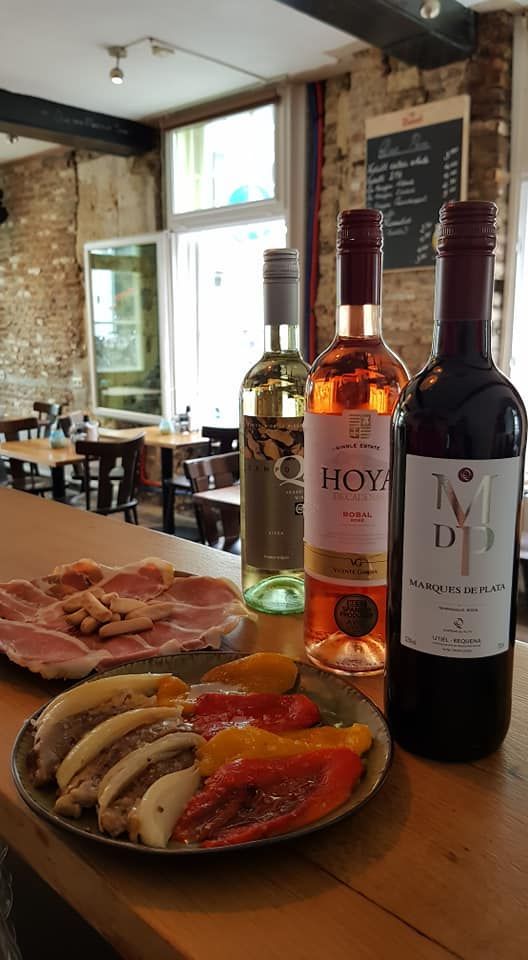 two bottles of wine are sitting on a wooden table next to a plate of food .