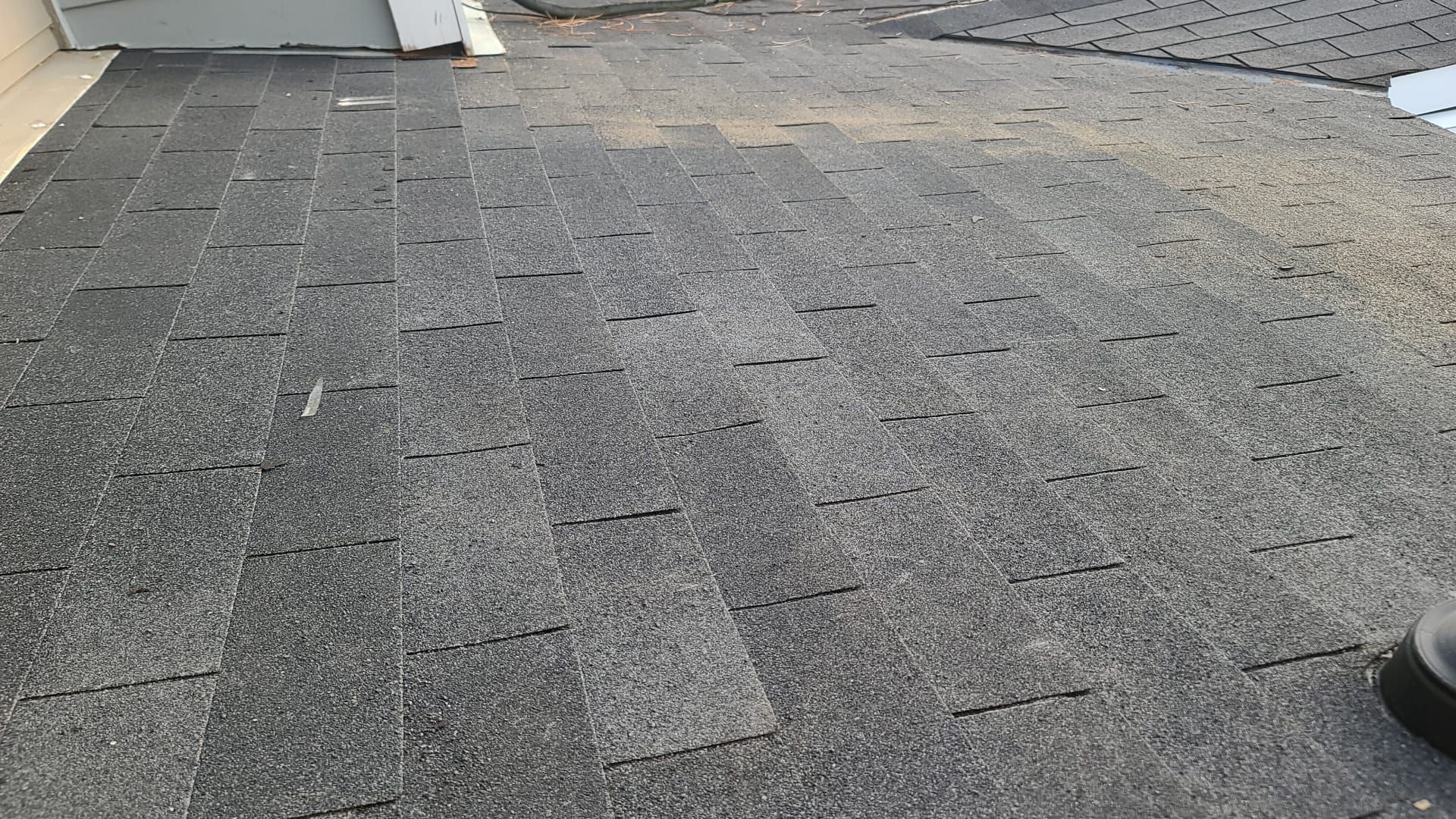 Flat gray rooftop with gravel, a vent pipe, and a dark shoe at the edge