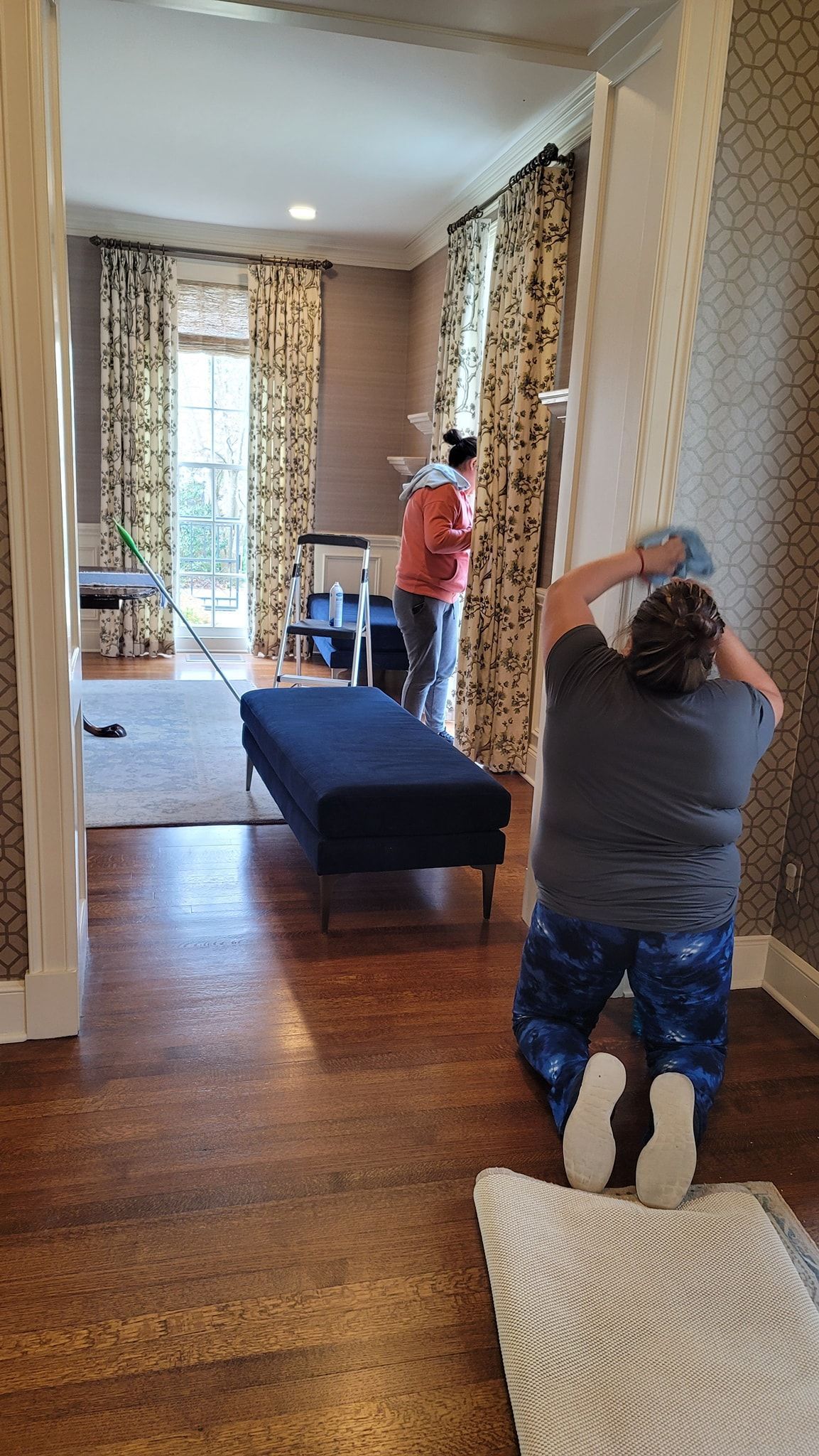 Person kneeling on carpet photographing a long hallway with exposed brick walls and a blue bench