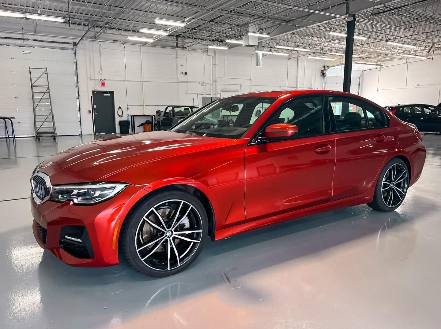A red bmw 3 series is parked in a garage.