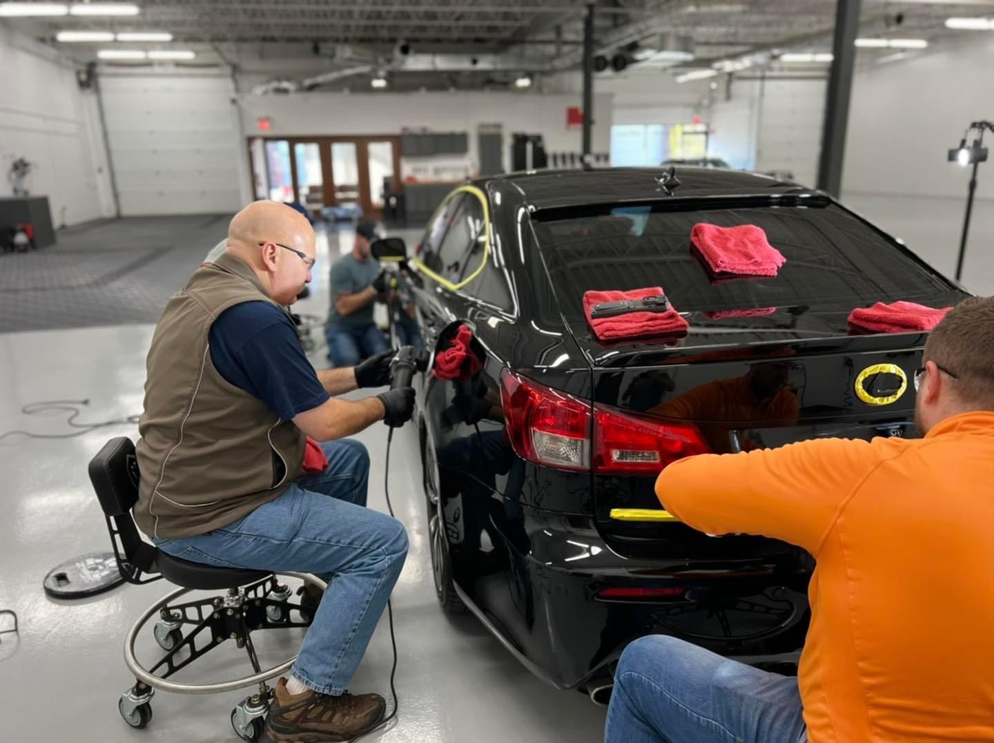 Two men are working on a black car in a garage.