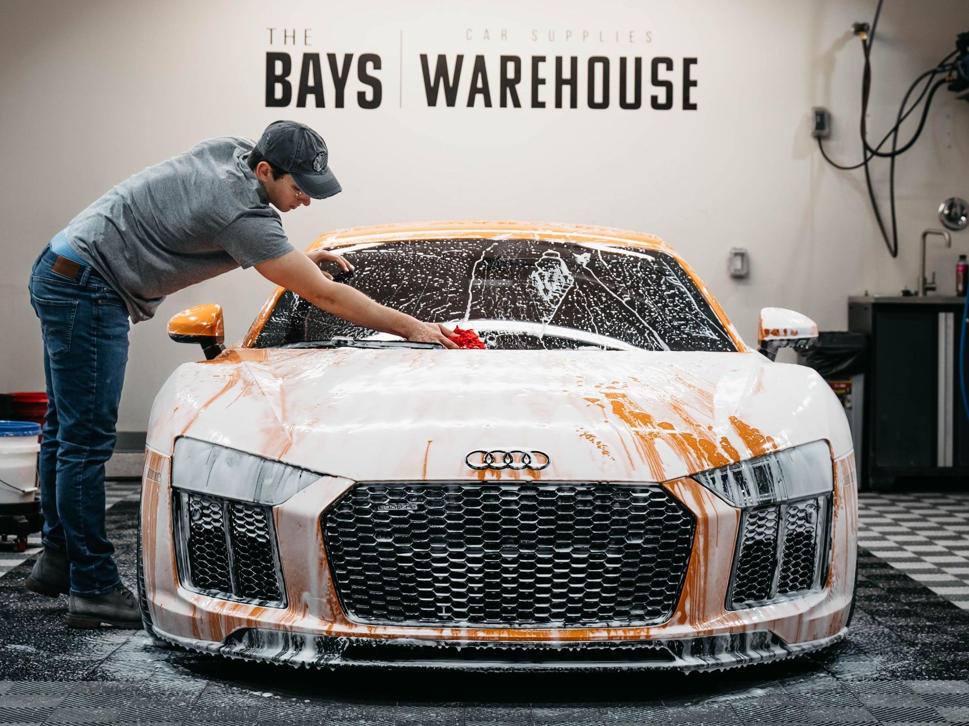 A man is washing a yellow car in a garage.