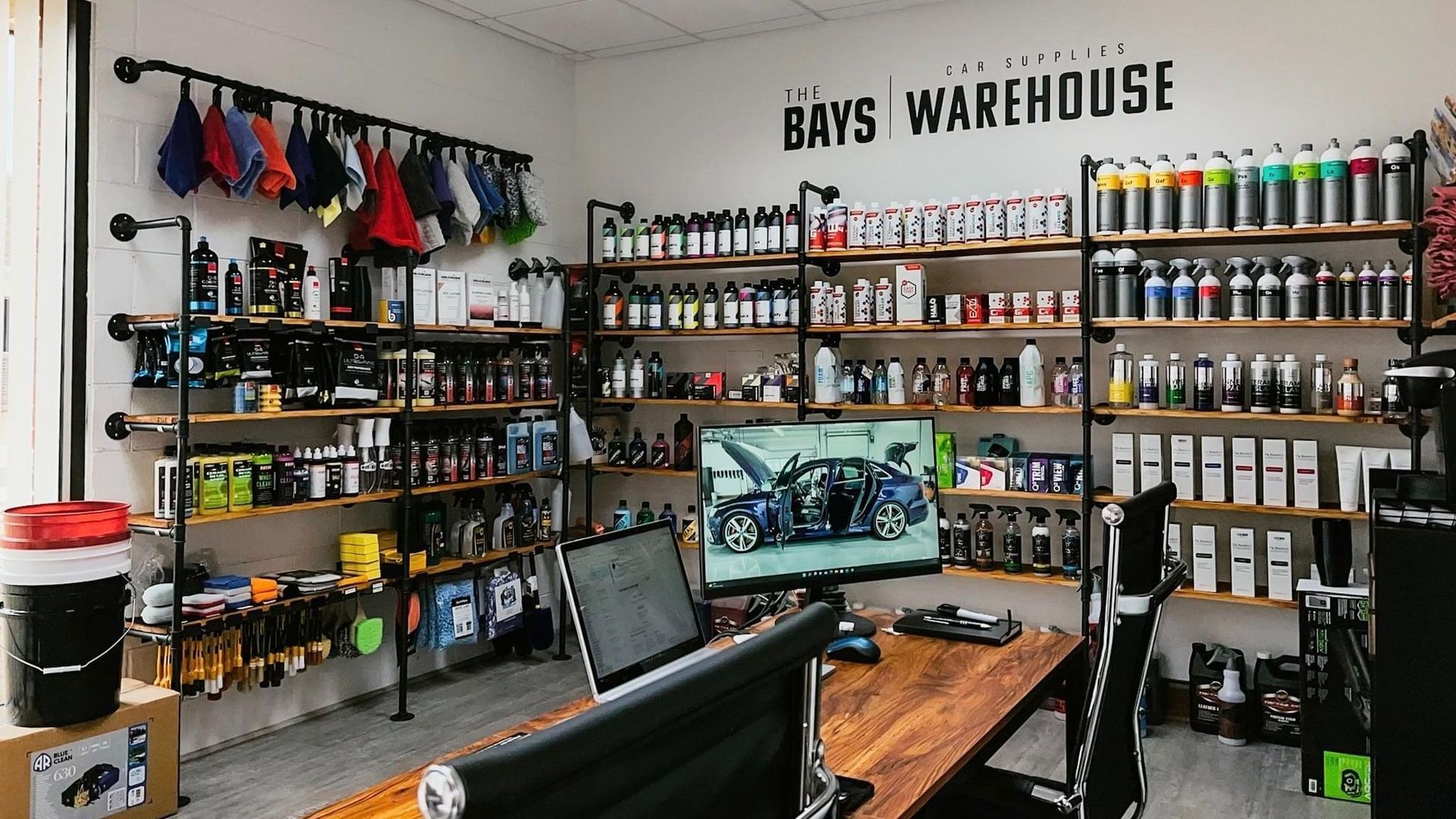 A warehouse filled with lots of products and a desk with a computer on it.