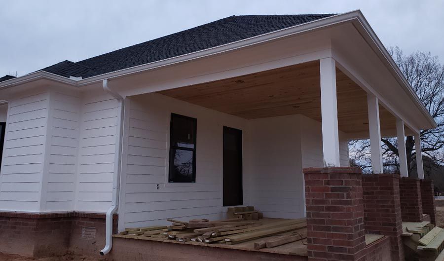 A white house with a black roof and a porch