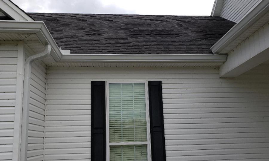 A white house with black shutters and a black roof.