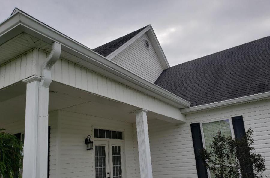 A white house with a black roof and a porch