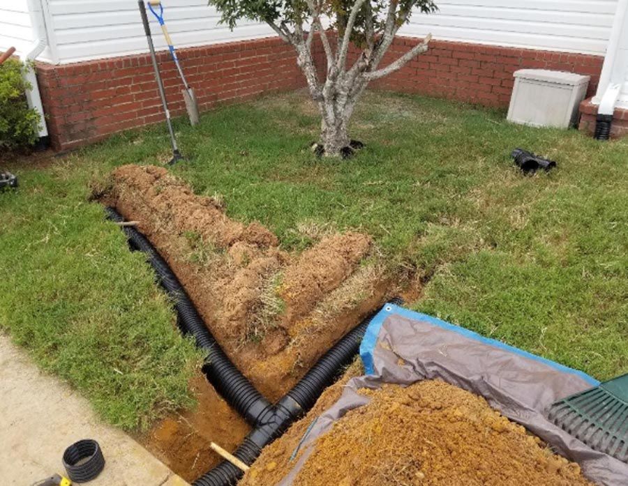 A drainage system is being installed in the backyard of a house.