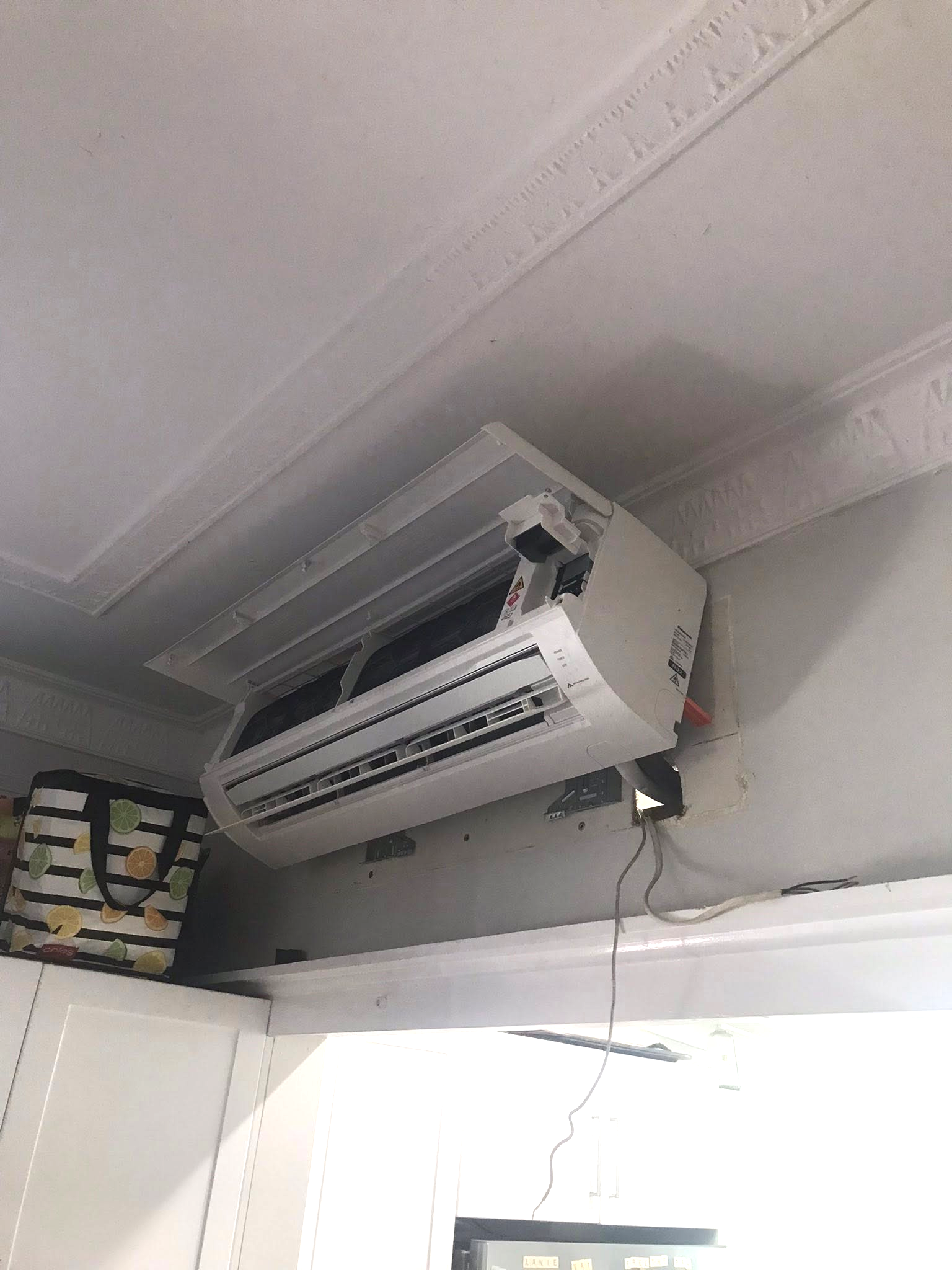Wall-mounted Air Conditioner Above White Cabinets In A Small Kitchen Area — Escarpment Air in Shellharbour, NSW