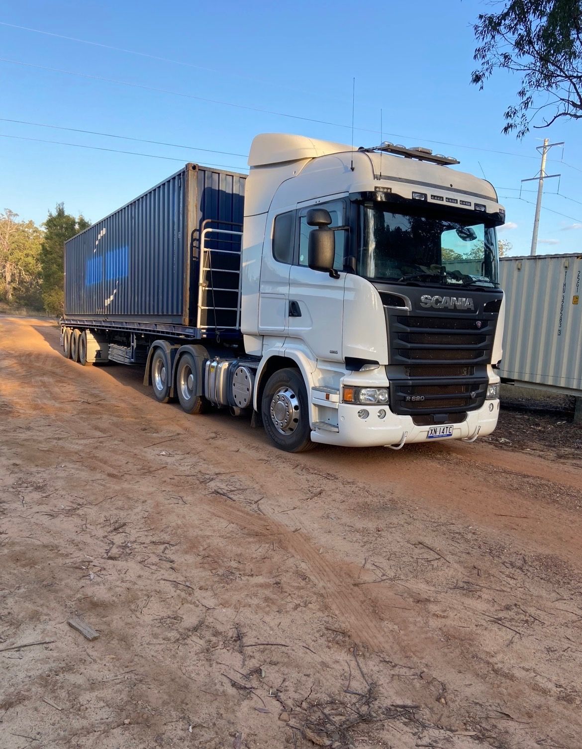 White Scania Semi-truck Hauling a Blue Shipping Container on a Dirt Road — Western Pacific Operations in Grafton, NSW