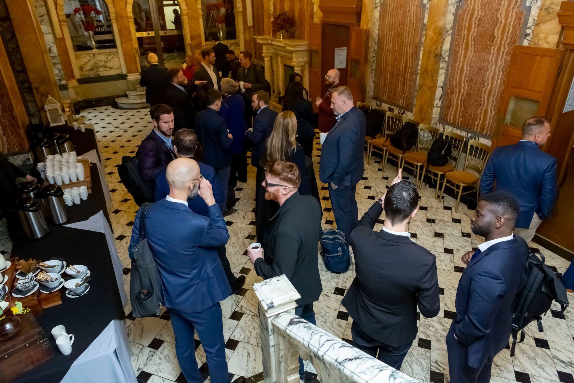 A group of people are standing in a room talking to each other.