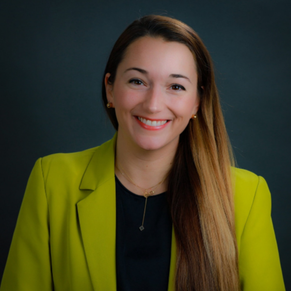 The woman is wearing a yellow jacket and smiling for the camera.