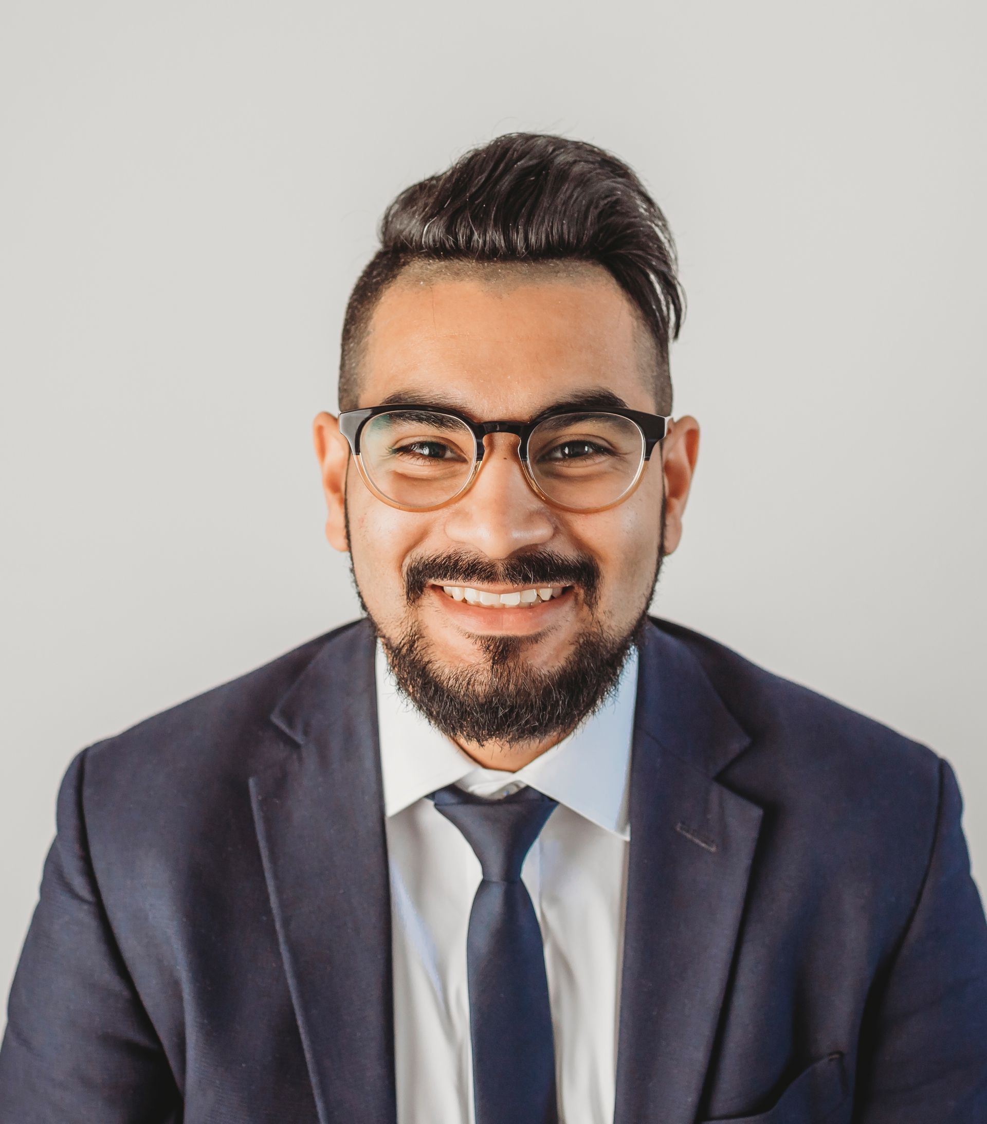A man with a beard and glasses is wearing a suit and tie.