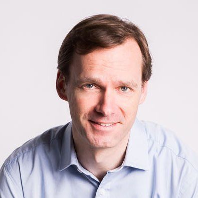 A man in a blue shirt is smiling for the camera.