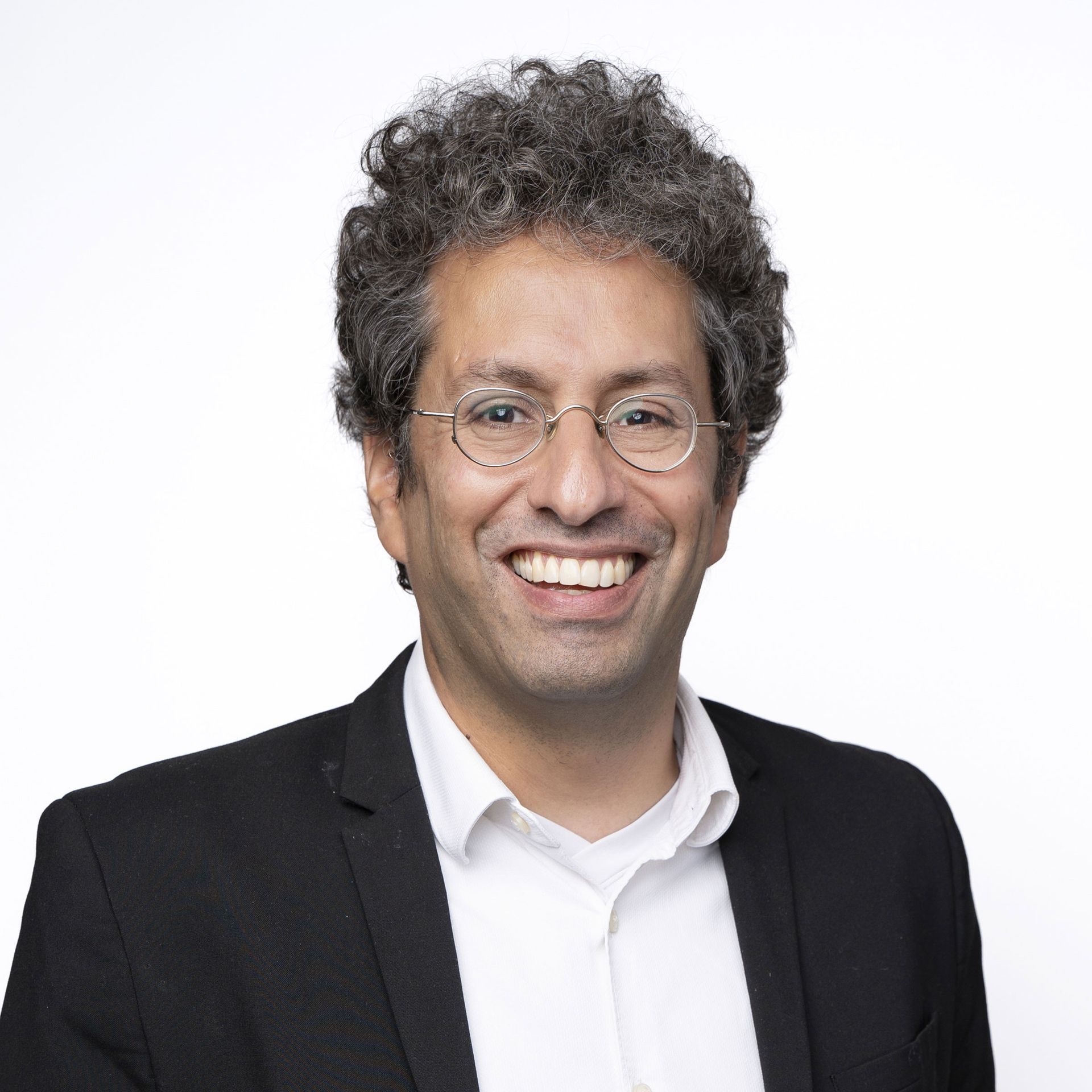 A man wearing glasses and a suit is smiling for the camera.