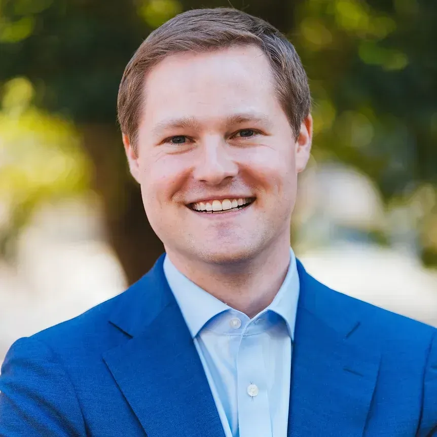 A man in a blue suit and white shirt is smiling for the camera.