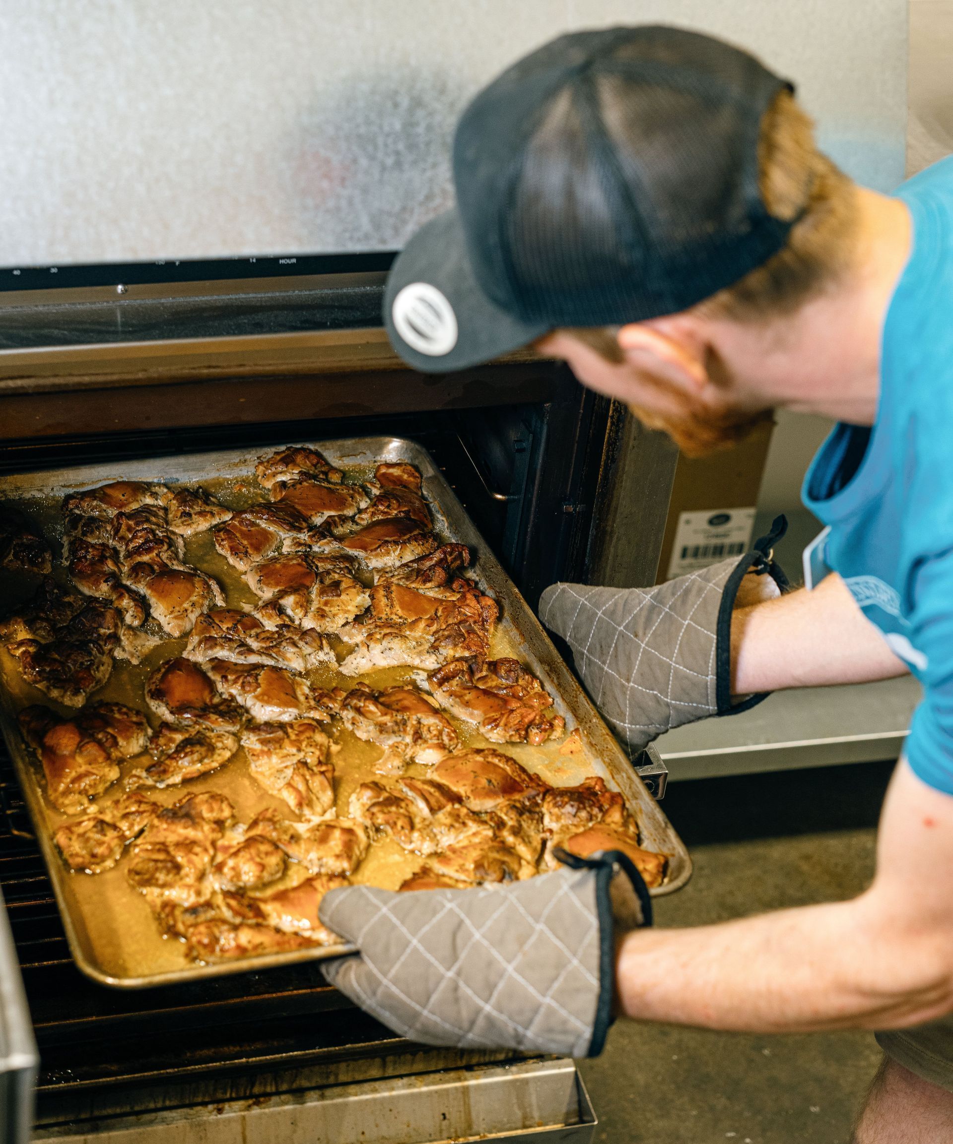 A man is taking a tray of food out of an oven