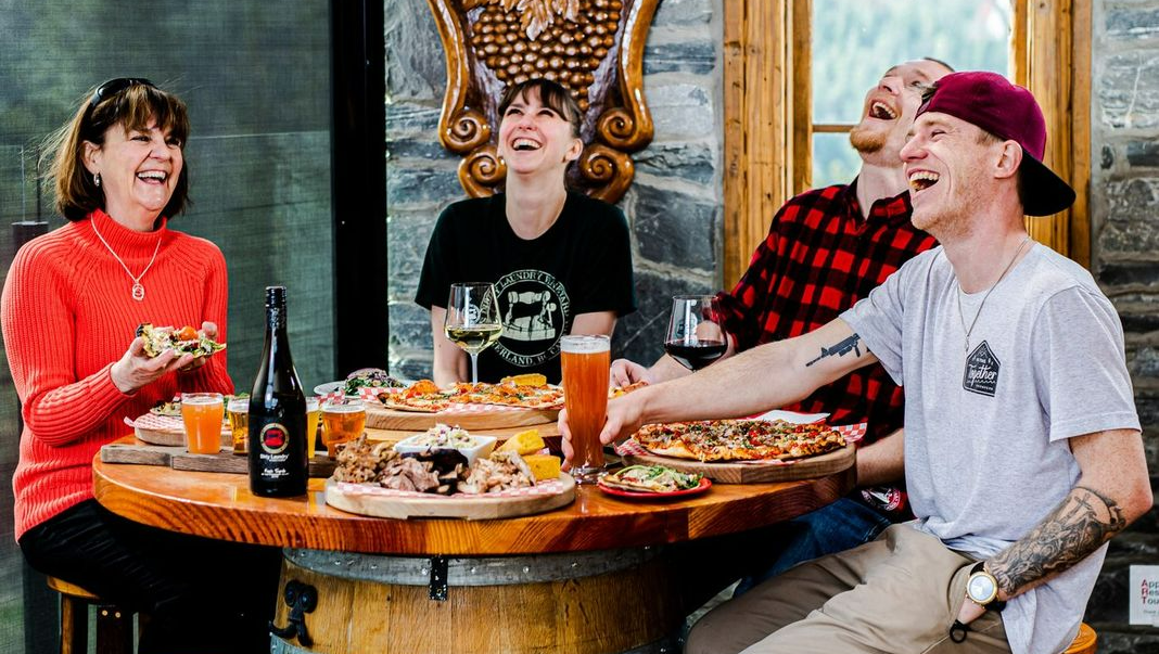 A group of people are sitting at a table eating pizza and drinking beer.