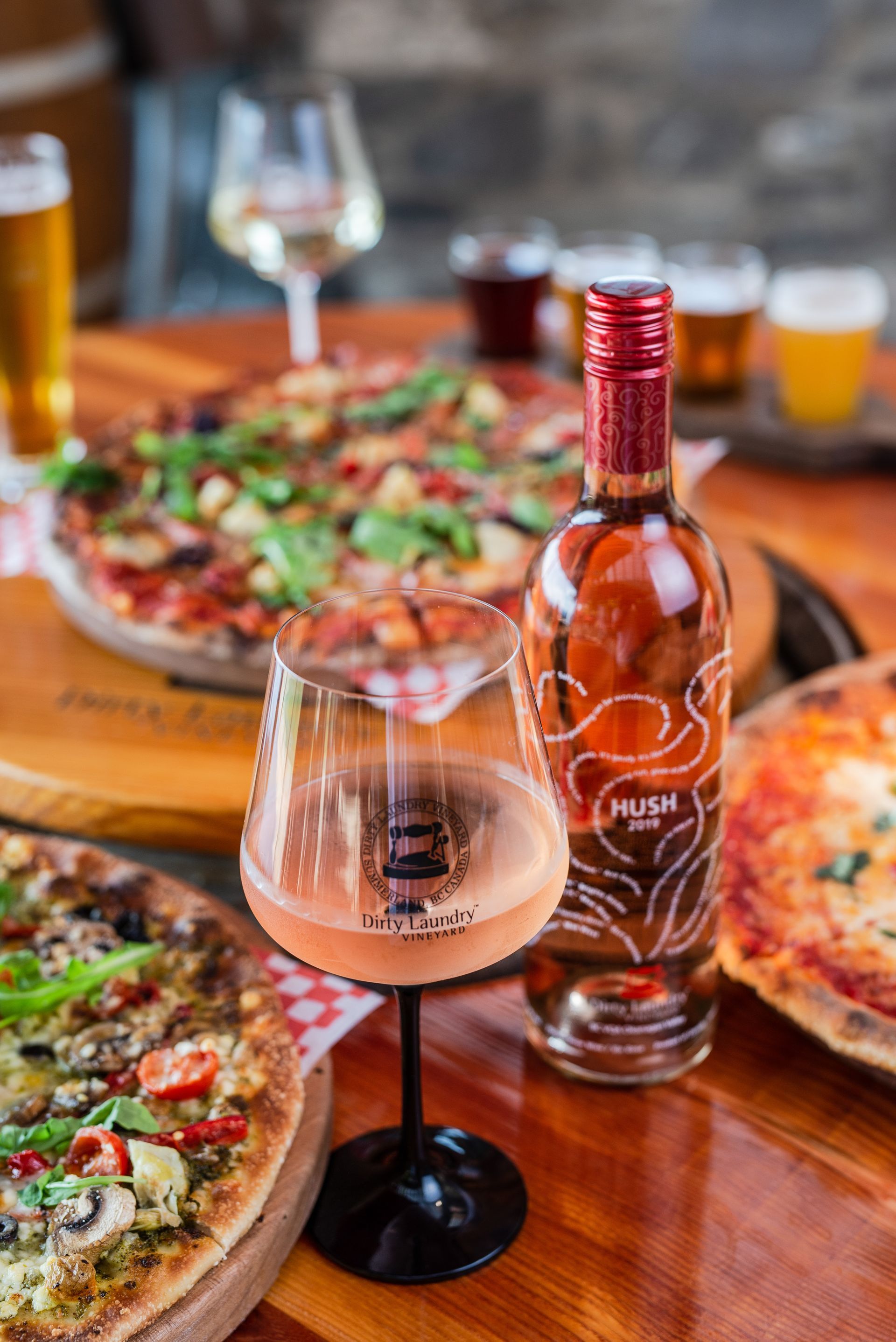 A bottle of wine is sitting on a wooden table next to a glass of wine.