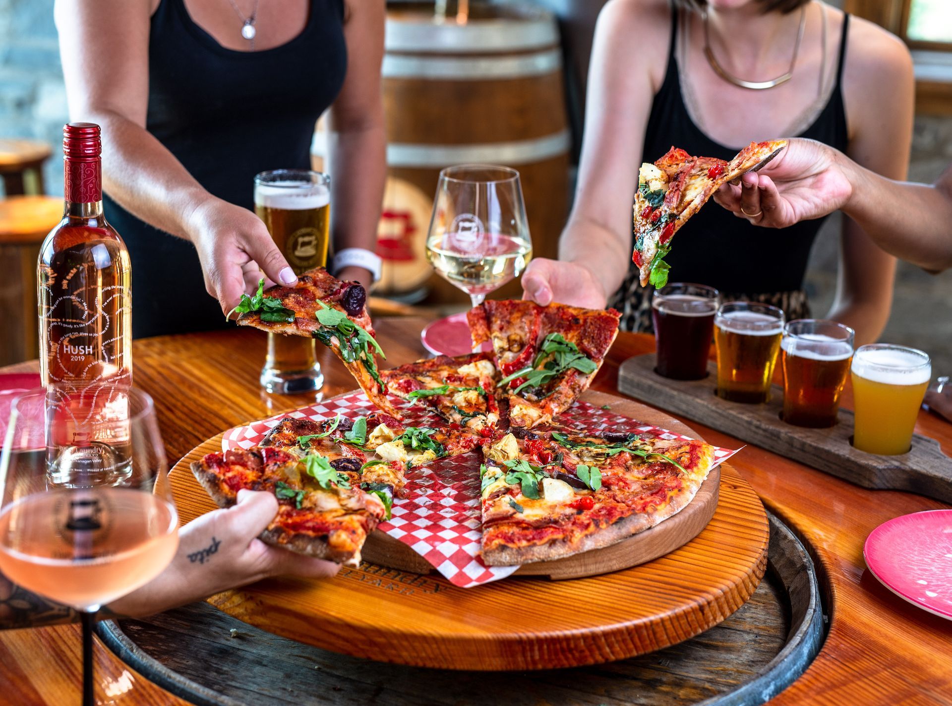A group of people are sitting at a table eating pizza and drinking beer.