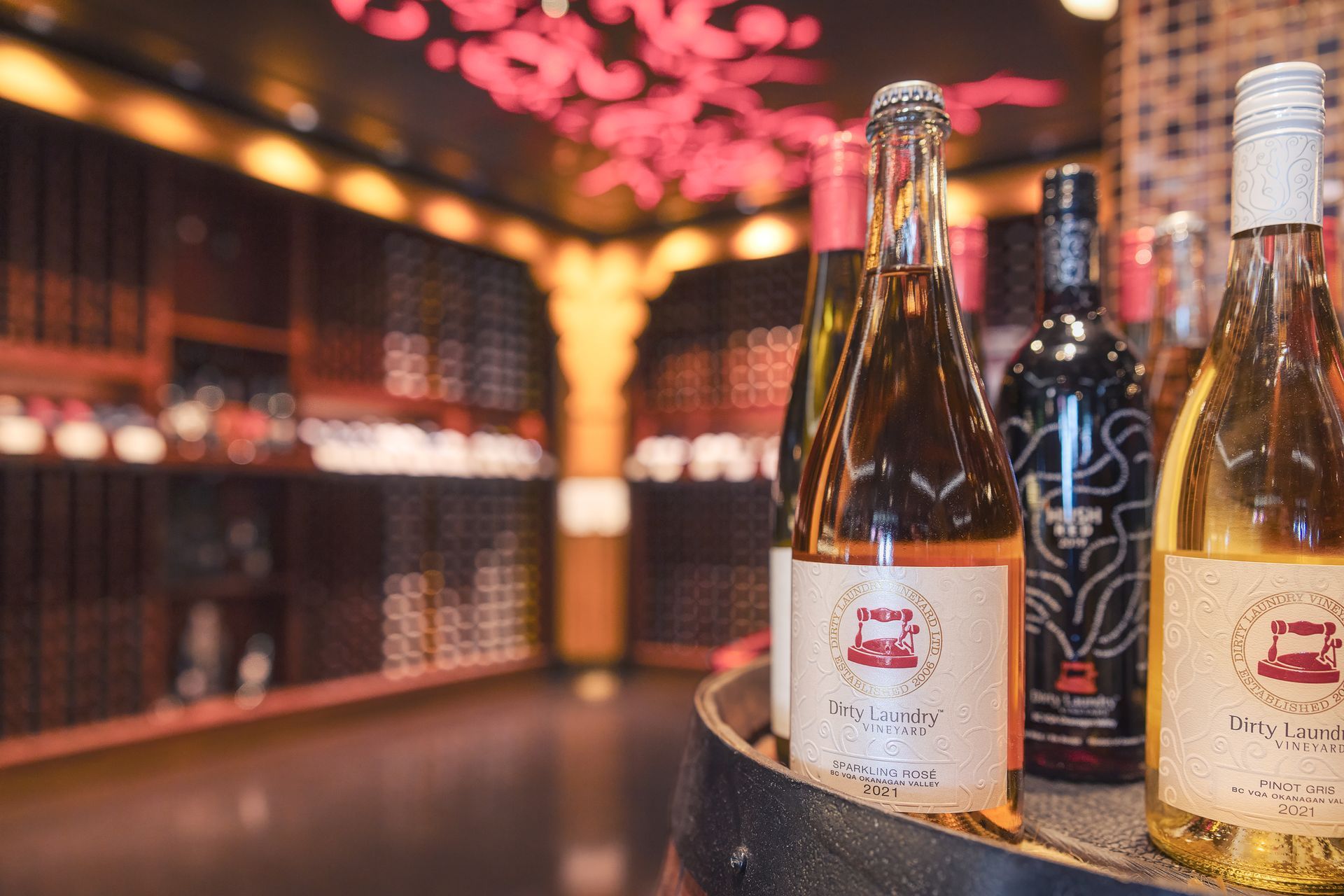 Bottles of wine are sitting on a barrel in a wine cellar.