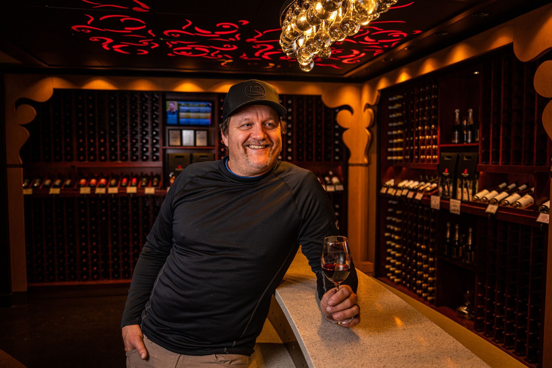 A man is holding a glass of wine in a wine cellar.
