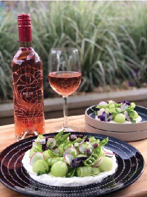 A bottle of wine and a glass of wine are on a table next to a plate of food.