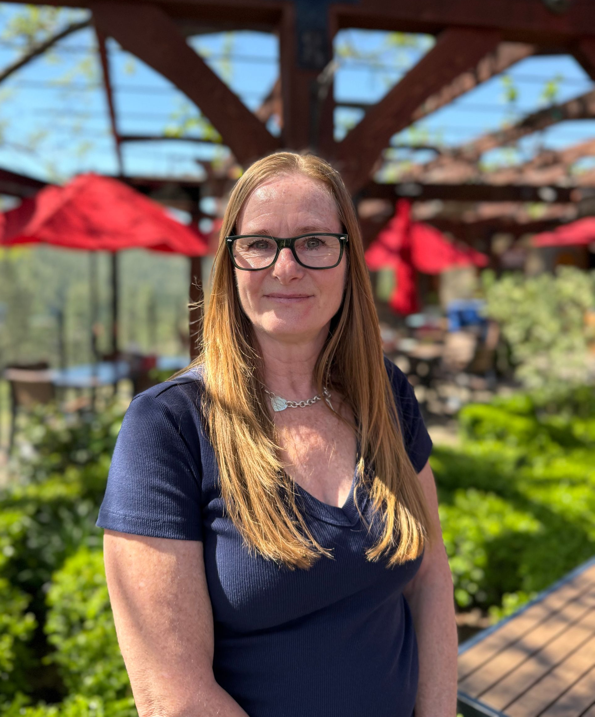 A man is sitting on a barrel holding a bottle of wine.