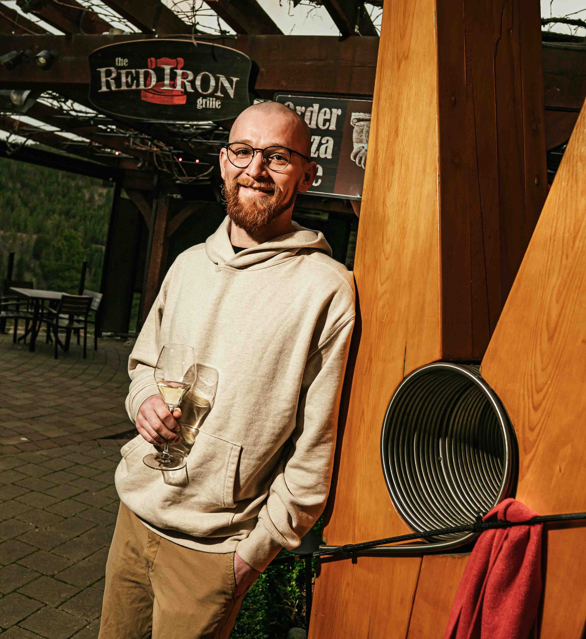 A man is sitting on a barrel holding a bottle of wine.