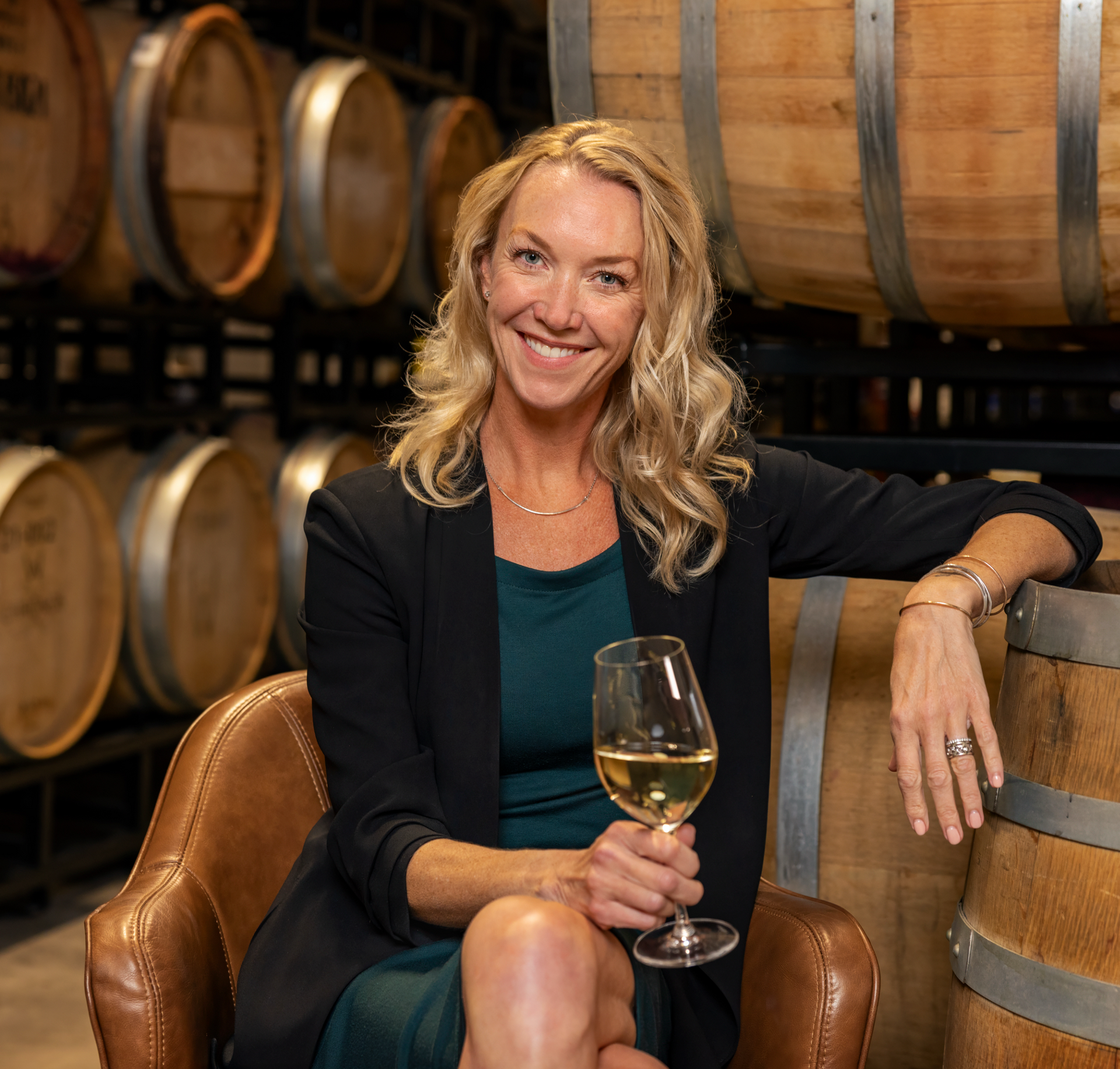 A woman wearing glasses is holding a glass of wine