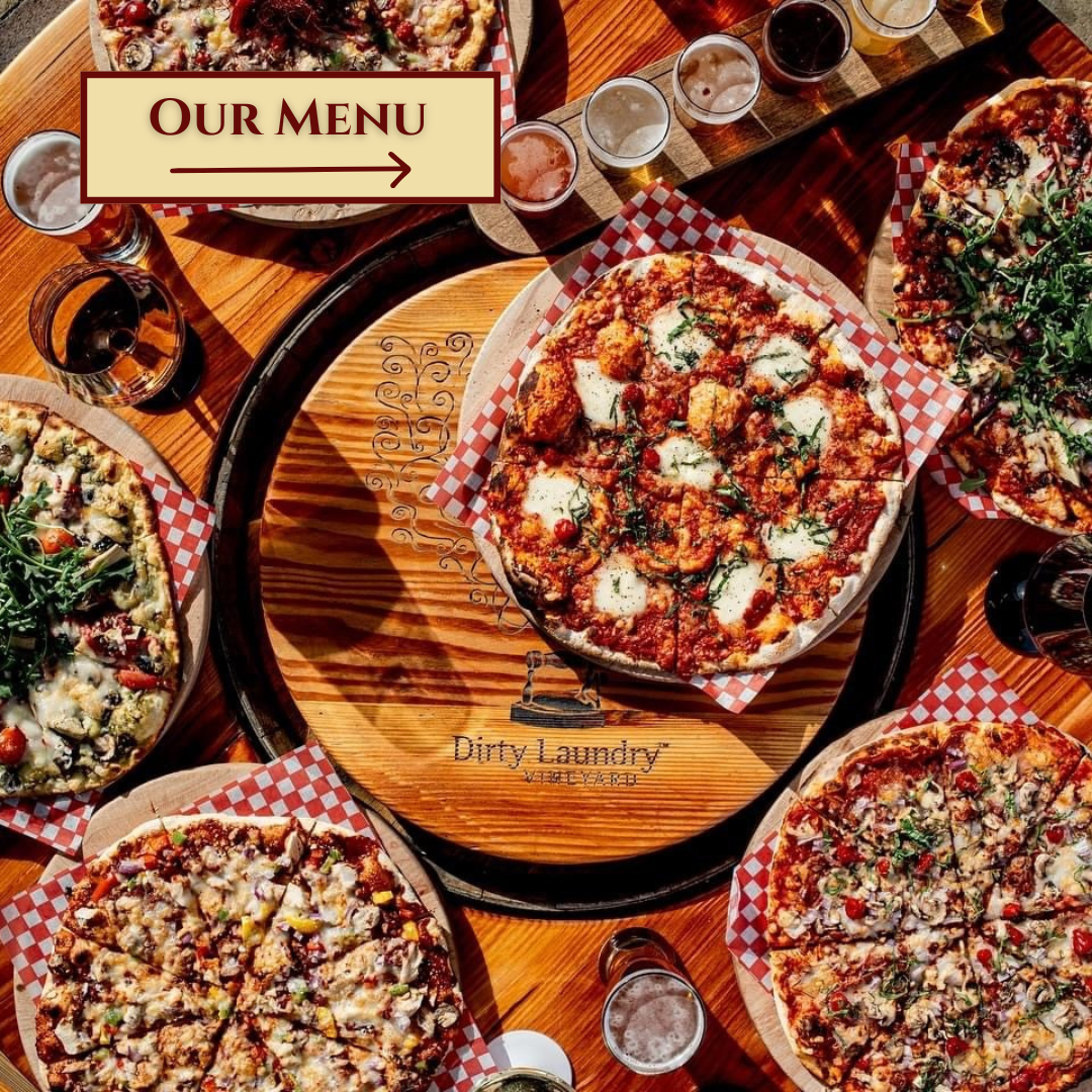 A wooden table topped with pizzas and a sign that says our menu
