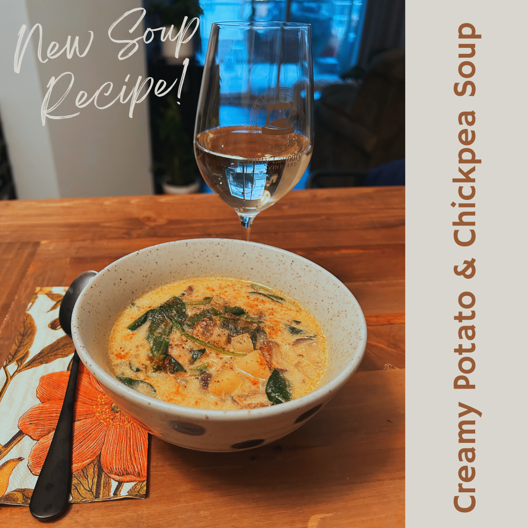A bowl of creamy potato and chickpea soup next to a glass of wine