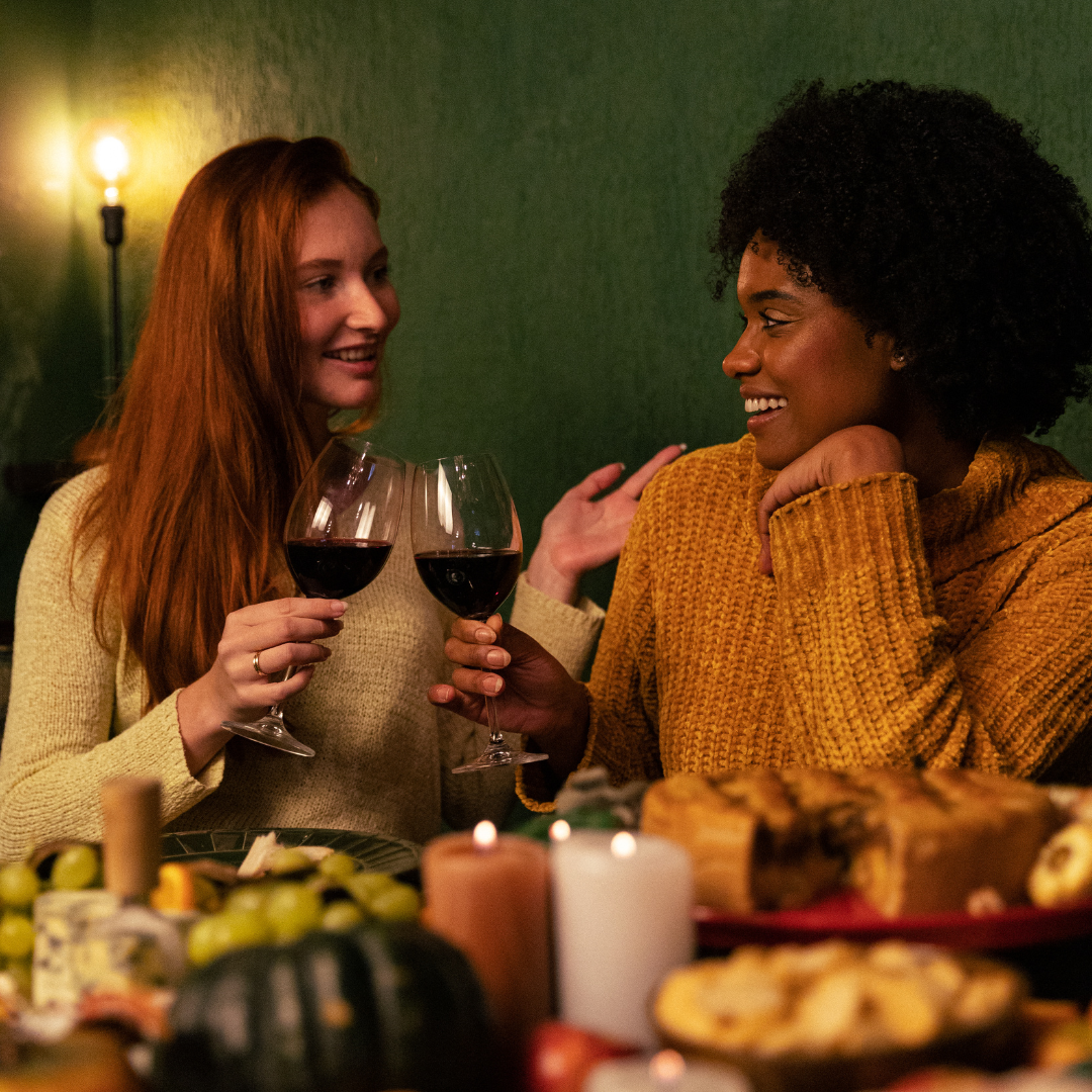 Two women are sitting at a table holding wine glasses.