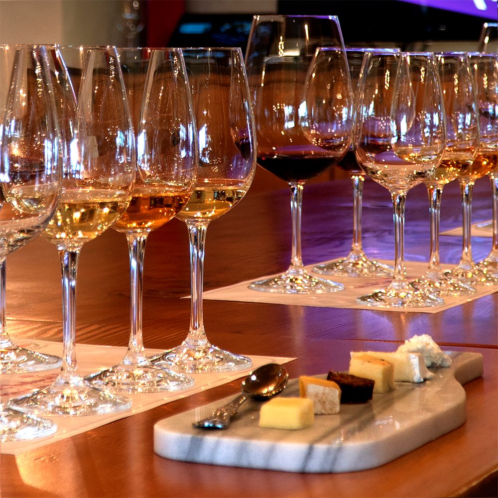 A tray of cheese sits on a table next to wine glasses