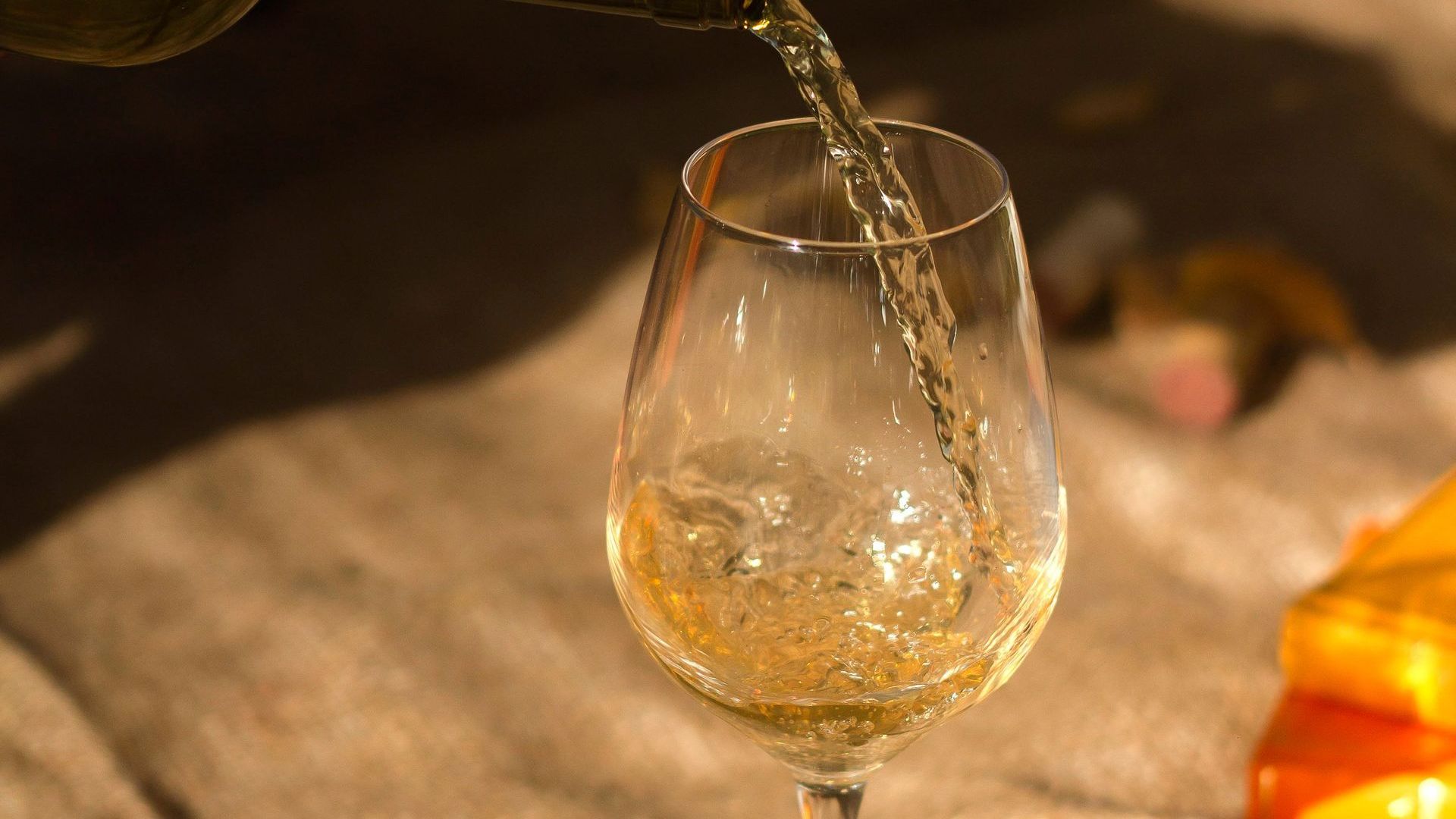 A glass of wine is being poured into a glass on a table.