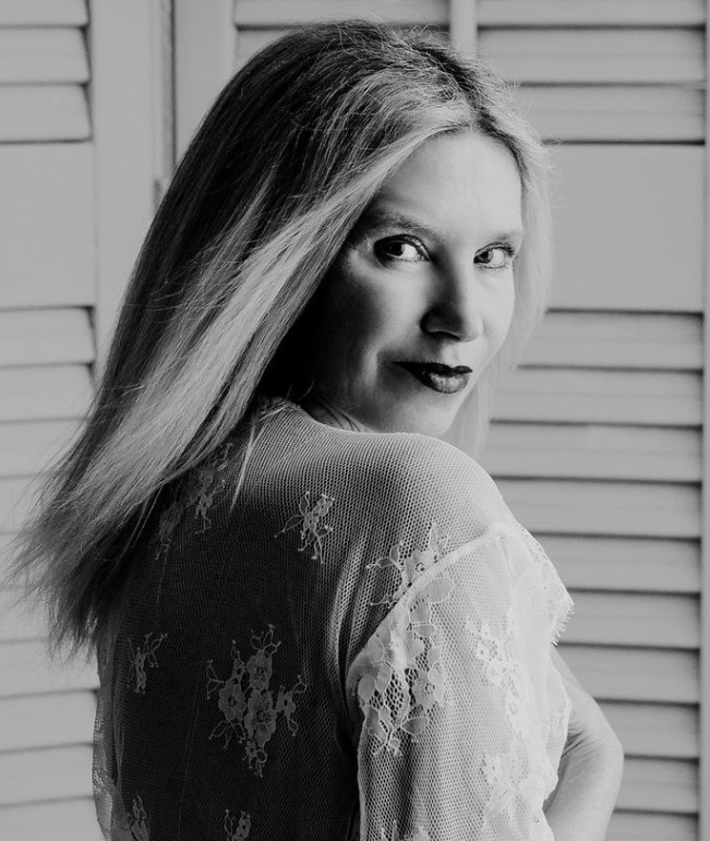 Ein Schwarzweissfoto einer Frau in einem Spitzenkleid, die über ihre Schulter schaut.