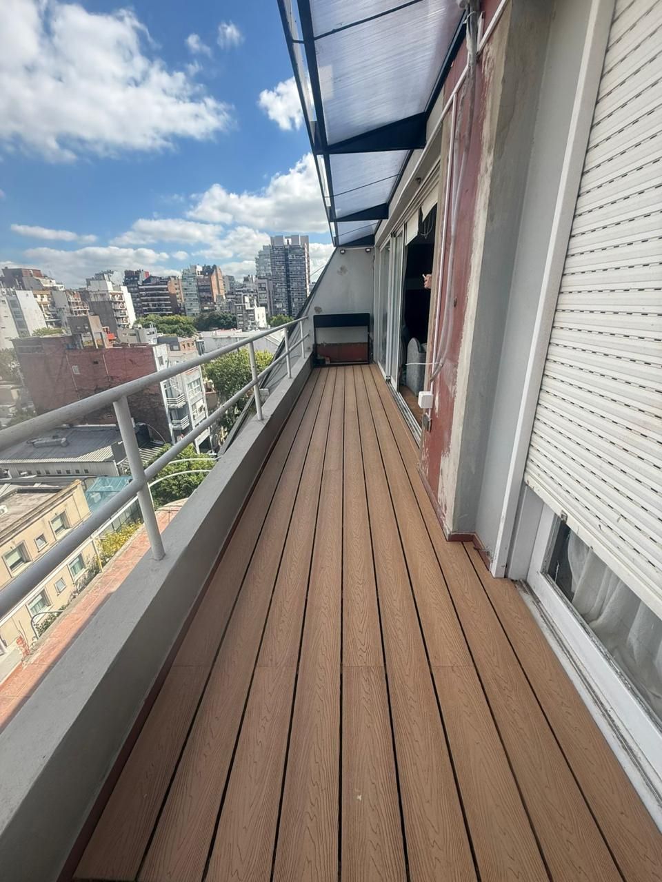 Dos trabajadores alinean las tablas de madera de la terraza con un nivel, mientras un tercero