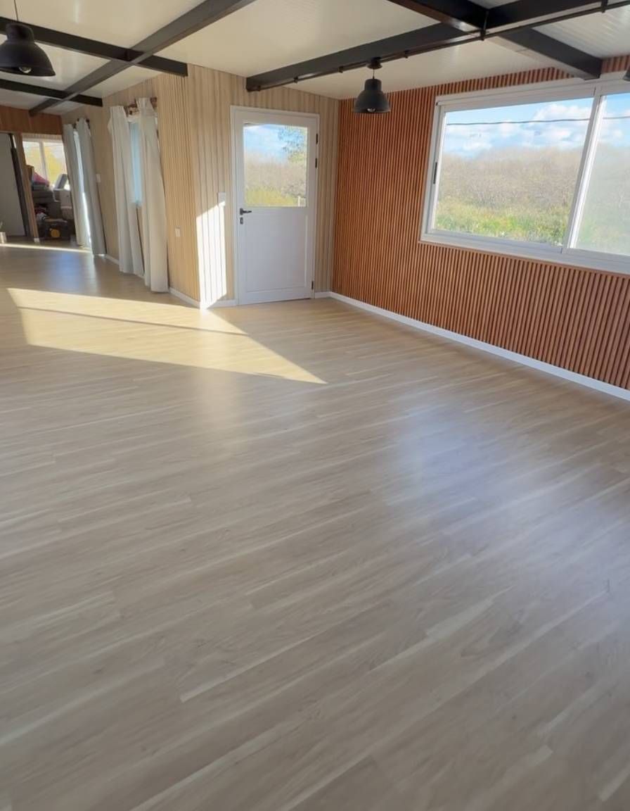 Manos con bata blanca utilizando una pequeña herramienta sobre una mesa de madera en un taller o laboratorio.