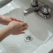 A person is washing their hands in a bathroom sink.