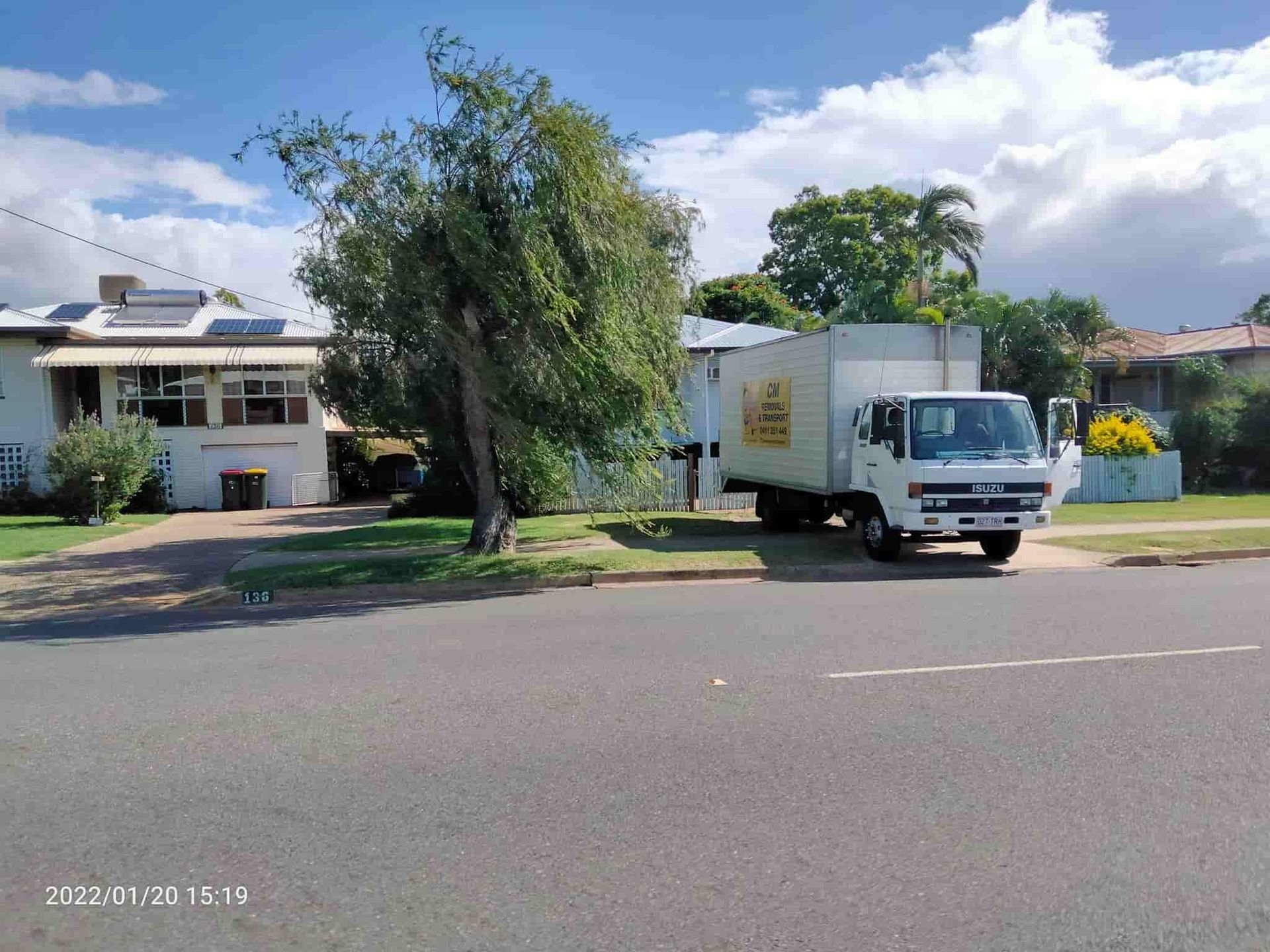 a White Truck is Parked on the Side of the Road in Front of a House — CM Removals & Transport In Bundaberg, QLD