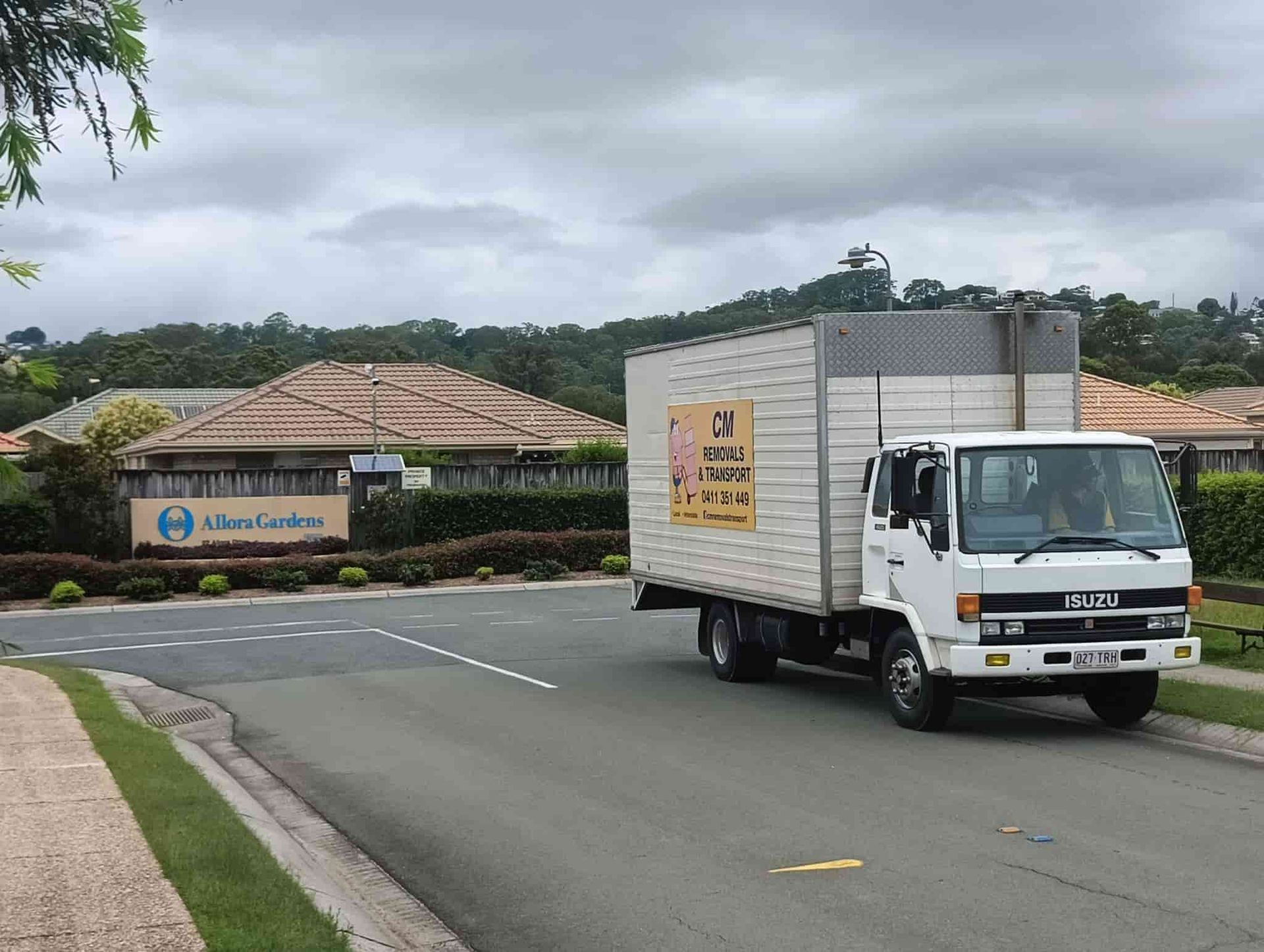 a White Truck is Driving Down a Street in Front of a Building — CM Removals & Transport In Maryborough, QLD